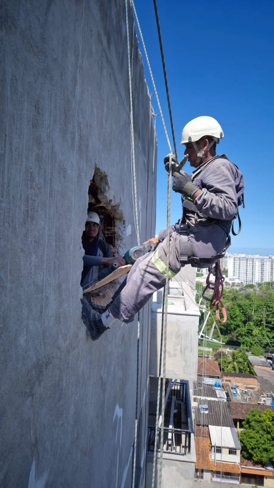 Profissional da JFS executando trabalho em altura com acesso por cordas na fachada de um edifício